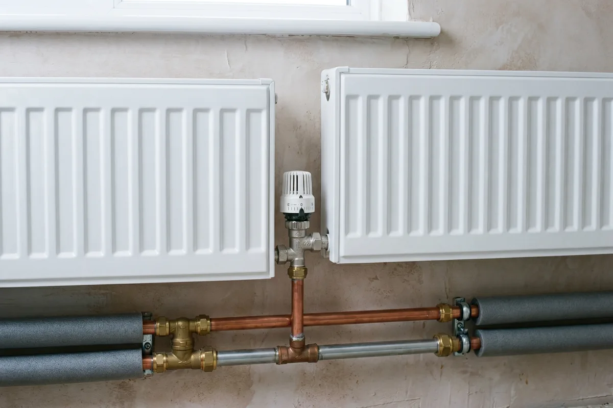 Heizkörper mit Thermostatventil und Kupferleitungen in einem Altbau