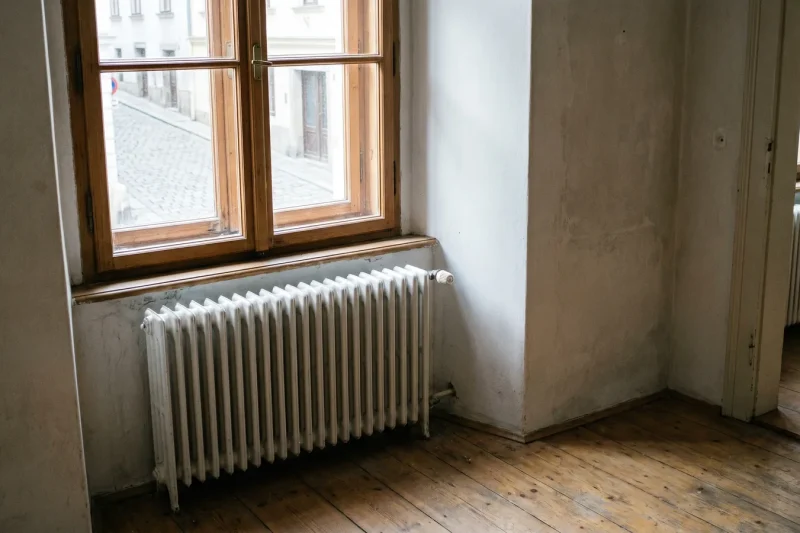 Klassischer Gliederheizkörper unter einem Sprossenfenster in einem renovierten Altbauzimmer