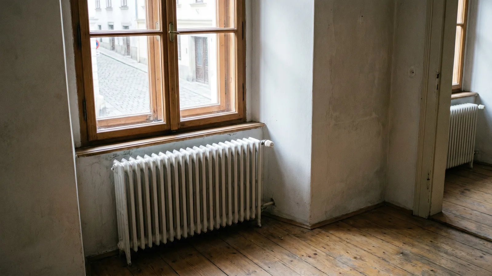 Klassischer Gliederheizkörper unter einem Sprossenfenster in einem renovierten Altbauzimmer